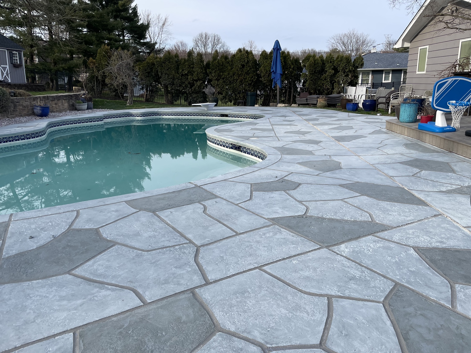 Resurfaced concrete pool deck in Granite Boulder finish showing modern gray stone appearance.