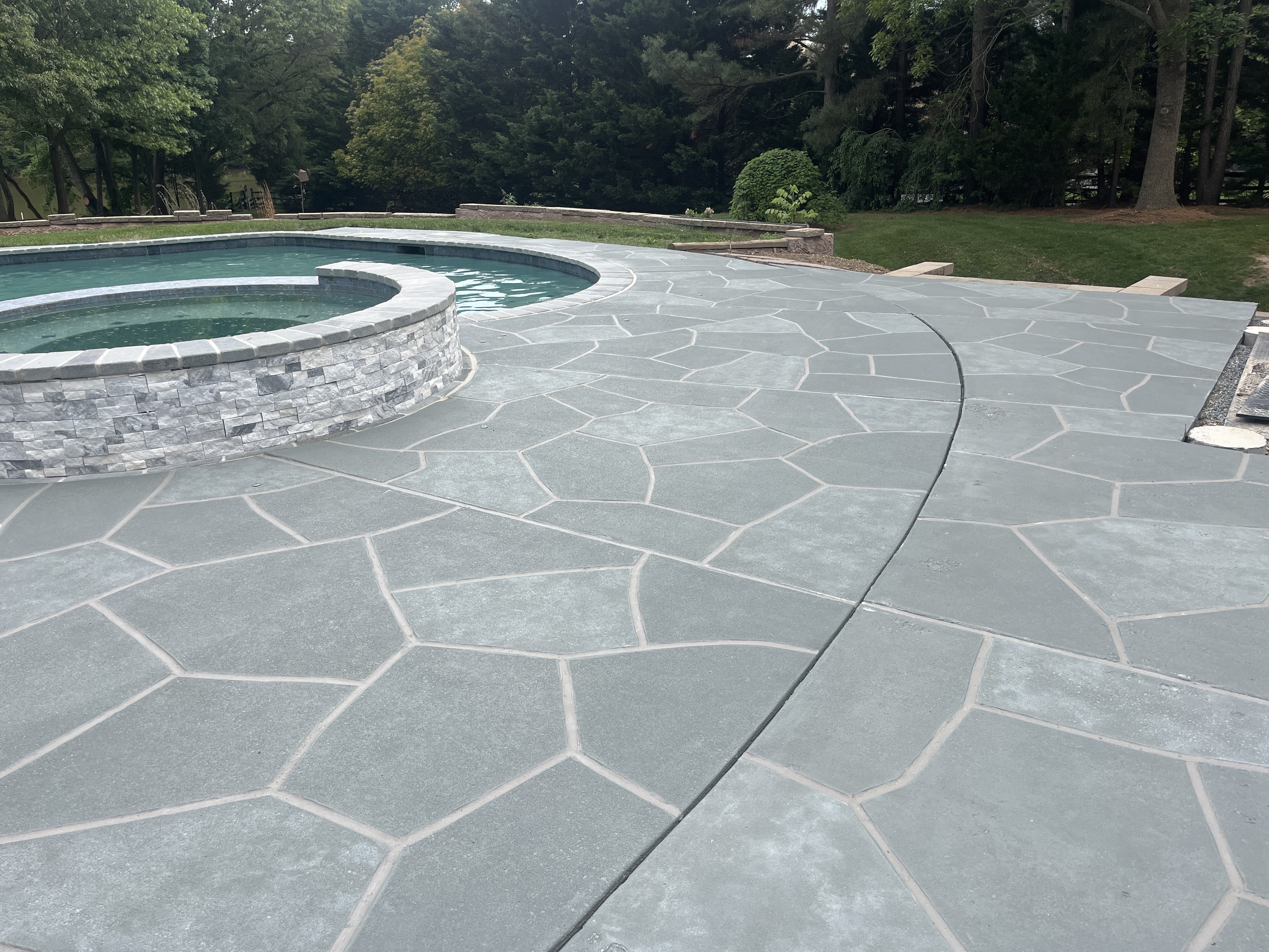Pool deck resurfaced in Granite Boulder finish with deep gray granite tones