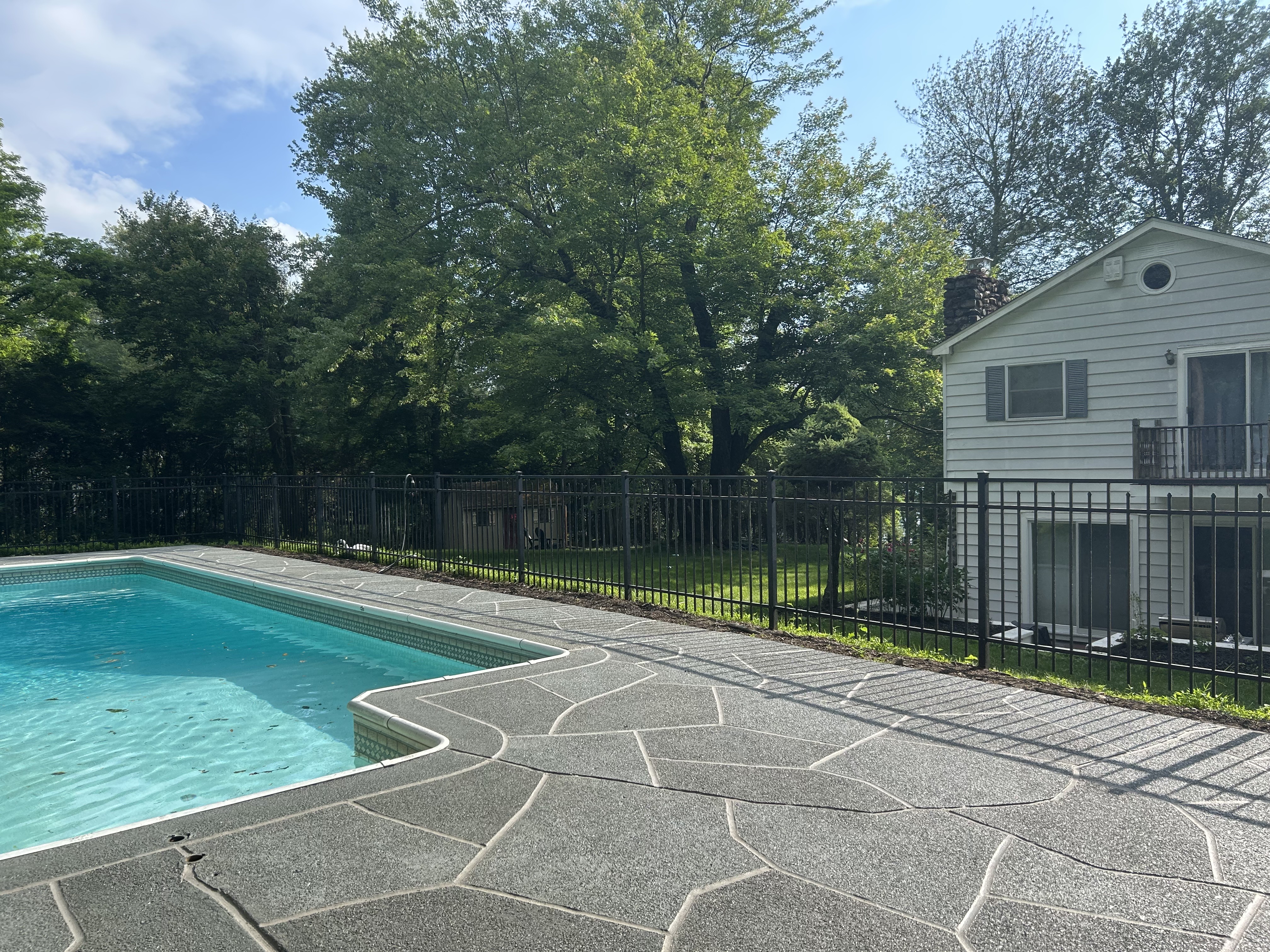Resurfaced concrete pool deck in Granite Slate finish in Warwick, RI showing modern gray stone appearance.